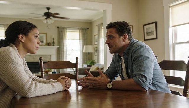 Couple having serious conversation over dining table in cozy home interior casual clothing