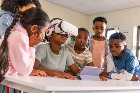 Diverse children exploring virtual reality and tablet collaboration in classroom learning