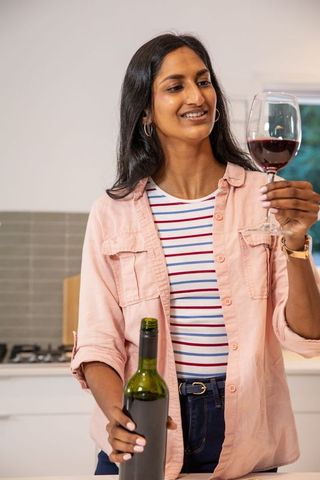 Woman Enjoying and Evaluating Glass of Red Wine in Modern Kitchen