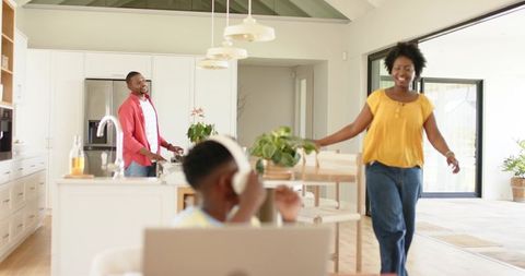African American family enjoying bright modern kitchen with child using laptop and headset
