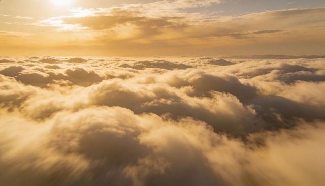 Soaring Above Golden Cloudscape at Sunrise with Layered Cumulus and Soft Sunlight