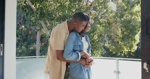 Romantic Couple Embracing on Sunny Balcony with Serene Views