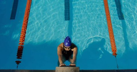 Swimmer preparing for race at outdoor pool with blue water