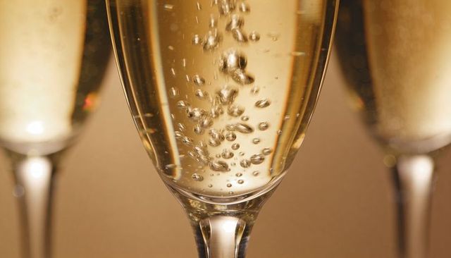 Elegant golden champagne flute sparkling with rising bubbles for celebration and toast