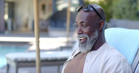 Senior African Man Reclining by Pool Smiling and Relaxing in Sunglasses at Resort