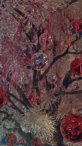 Tilting Vertical Video into Shimmering Red and Silver Christmas Tree Ornaments and Tinsel