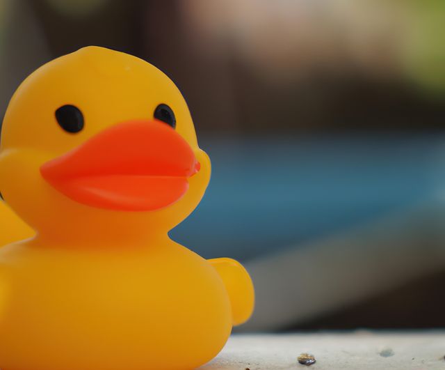 Close up of yellow rubber duck on blurred background created using generative ai technology. Toy, material and animals concept, digitally generated image.