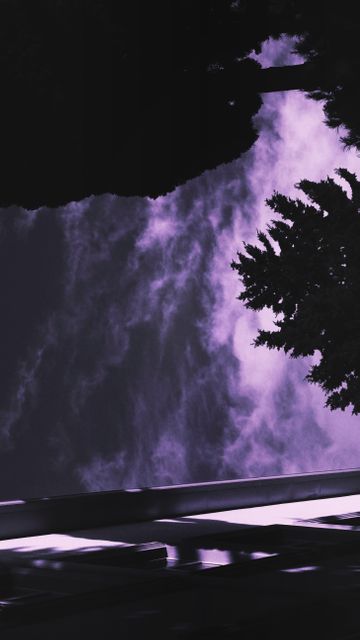 Depicts a serene and surreal night sky with purple clouds and silhouette of trees creating a mysterious atmosphere. Ideal for backgrounds, posters, digital art projects, and serene decor elements. Can be used in blogs or articles about nature's tranquility, relaxing themes, or artistic perspectives.