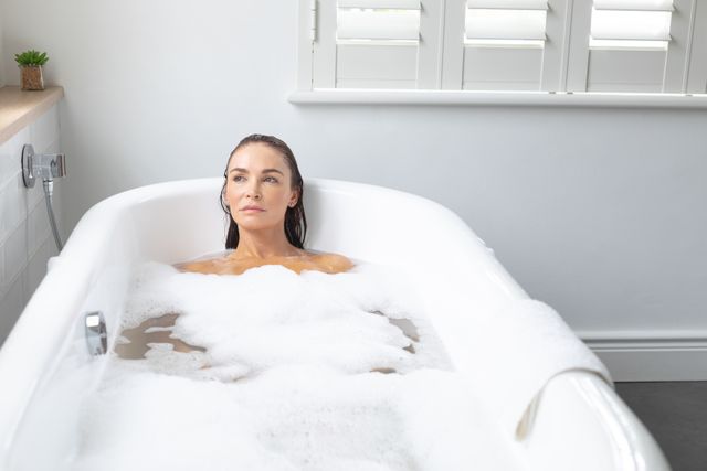 Beautiful woman taking bubble bath in bathroom at home