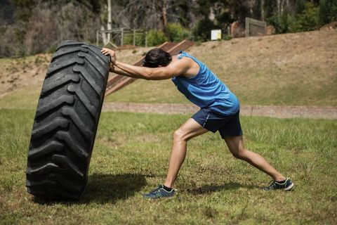 Male athlete demonstrating strength flipping heavy tractor tire outdoors