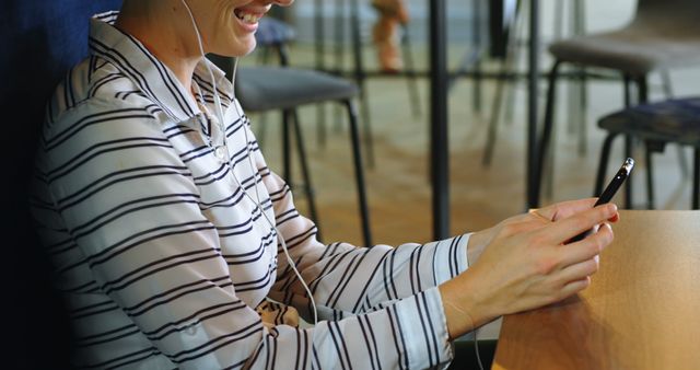 Woman Enjoying Music on Smartphone with Earphones in Modern Café - Download Free Stock Images Pikwizard.com