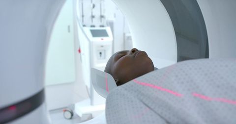 African american woman undergoing head mri with pink laser alignment in radiology suite