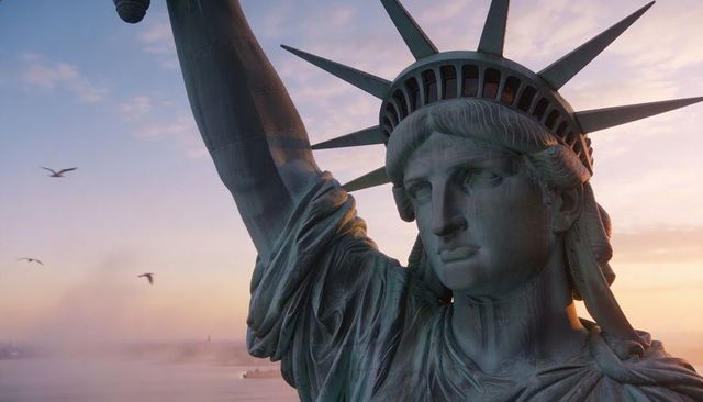 Statue of liberty at sunrise standing over harbor with copper patina, seagulls, ferry