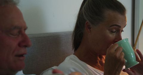 Senior couple drinking coffee in bed at home