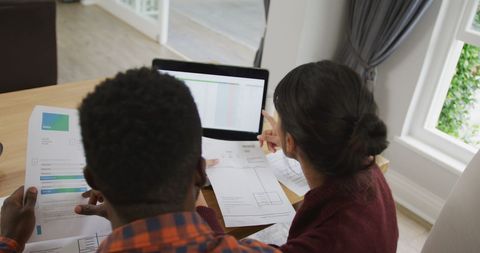 Couple Reviewing Finances at Home with Laptop on Table