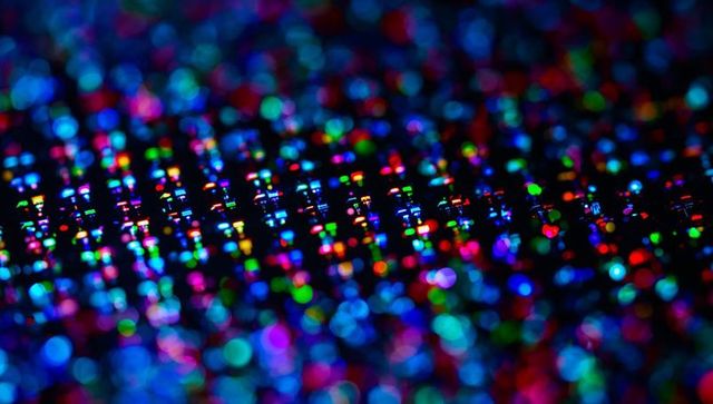 Shimmering holographic foil scattering light macro with prismatic bokeh and pixelated grid