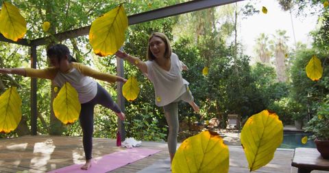Women Practicing Yoga amidst Falling Leaves in Tranquil Garden