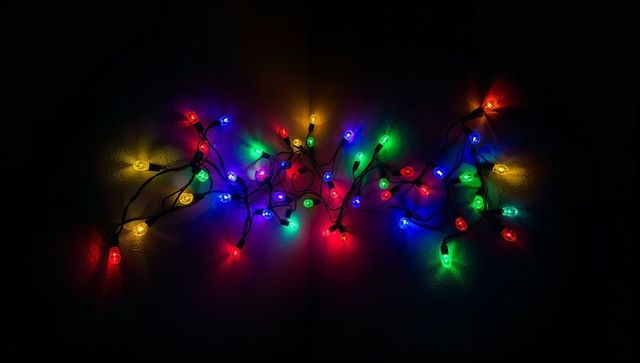 Glowing tangled multicolor led string lights casting colorful halos on dark wall