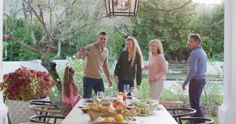 Multigenerational family taking selfie on patio during casual outdoor meal