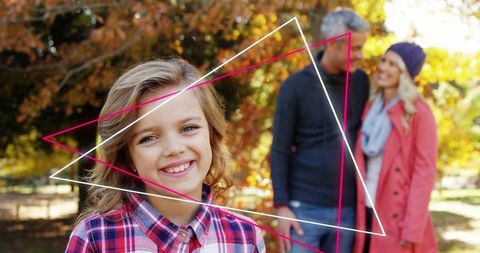 Smiling girl in plaid shirt with parents blurred in autumn park, magenta geometric overlays