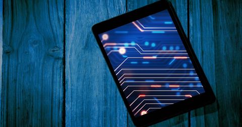 Tablet displaying digital circuitry background on rustic wood surface