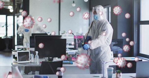 Hazmat technician spraying office disinfectant while virus particles float, PPE disinfection
