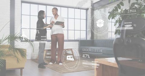 Female coworkers reviewing ar logistics dashboard on tablet in modern loft office