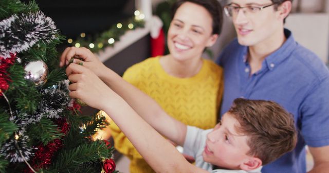 Happy caucasian parents and son decorating christmas tree at christmas. Spending quality time with family at home concept.