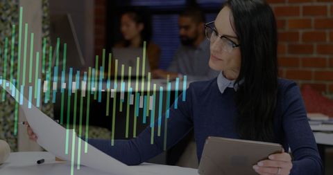 Businesswoman analysing data with tablet and graph overlays