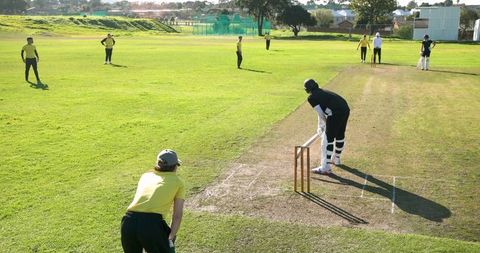 Teen Cricketers Playing on Sunny Field with Batsman near Wicket