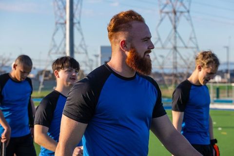 Male soccer team walking across field in sports jerseys outdoors