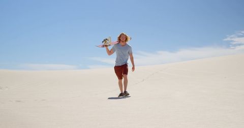 Man Strolling on Desert with Skateboard Under Sunny Sky