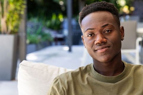 Relaxing african american man smiling on modern terrace lounge with greenery