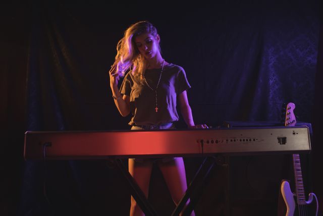 Female musician playing piano on stage in a nightclub with dim lighting and a spotlight. Ideal for use in articles about live music, nightlife entertainment, music performances, and promotional materials for concerts and music events.
