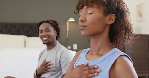 African american couple practicing breathwork and mindfulness on bed for calm wellbeing