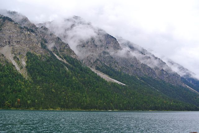 Misty Mountain Range by Tranquil Lake on Overcast Day - Download Free Stock Photos Pikwizard.com