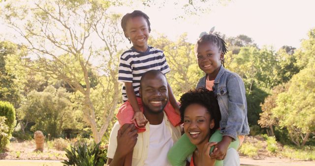 Happy African American family smiling while spending quality time outdoors. Perfect for topics related to family bonding, outdoor activities, parenting, happiness, summer outings, and healthy family relationships.