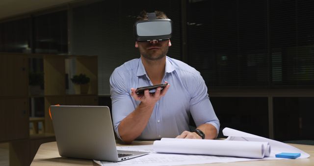 Man Using VR Headset and Smartphone at Desk with Laptop - Download Free Stock Images Pikwizard.com