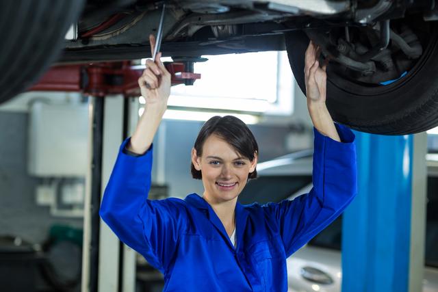 Female mechanic examining car wheel disc brake in repair garage