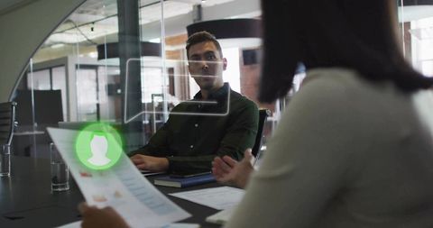 Recruiter reviewing resume with digital profile overlay in glass boardroom