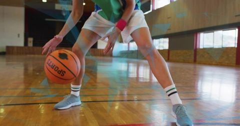 Female athlete dribbling basketball in low stance on indoor hardwood court