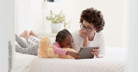 Mother and Daughter Bonding Over Tablet on Cozy Bed