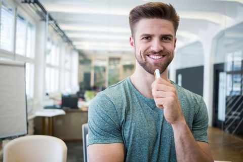 Smiling bearded professional with whiteboard marker in modern office space