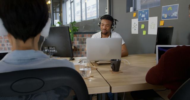 Young Professionals Working at Modern Office Desk with Headphones and Laptops - Download Free Stock Images Pikwizard.com