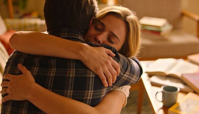Couple hugging in cozy living room showing relief and intimacy, warm home embrace