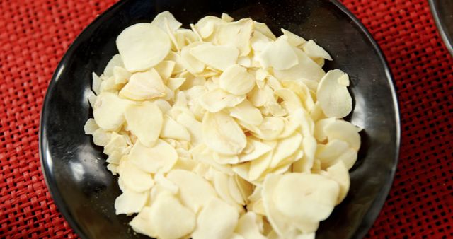 Close-Up of Freshly Sliced Garlic in Black Bowl on Red Background - Download Free Stock Images Pikwizard.com