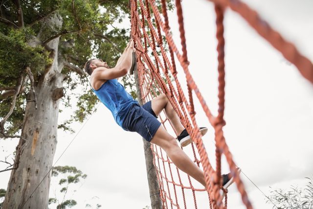 Man climbing a net during obstacle course in boot camp