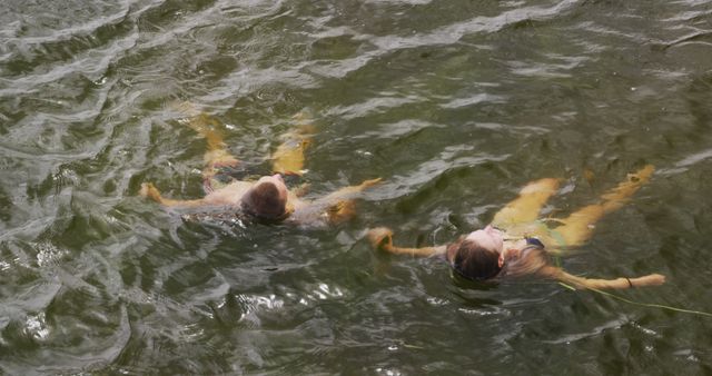 This image shows two women swimming peacefully in calm water, captured from an aerial perspective. It can be used for topics related to summer vacations, leisure activities, swimming, friendship, relaxation, and outdoor experiences. Ideal for use in travel magazines, blogs about vacation destinations, fitness and wellness articles, and lifestyle advertisements.