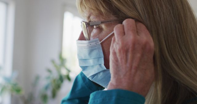 Senior Woman Putting On a Protective Face Mask at Home - Download Free Stock Images Pikwizard.com