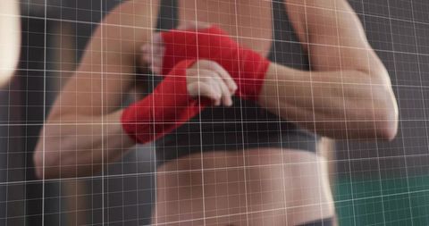 Female boxer adjusting red hand wraps before training in gym with mesh grid overlay